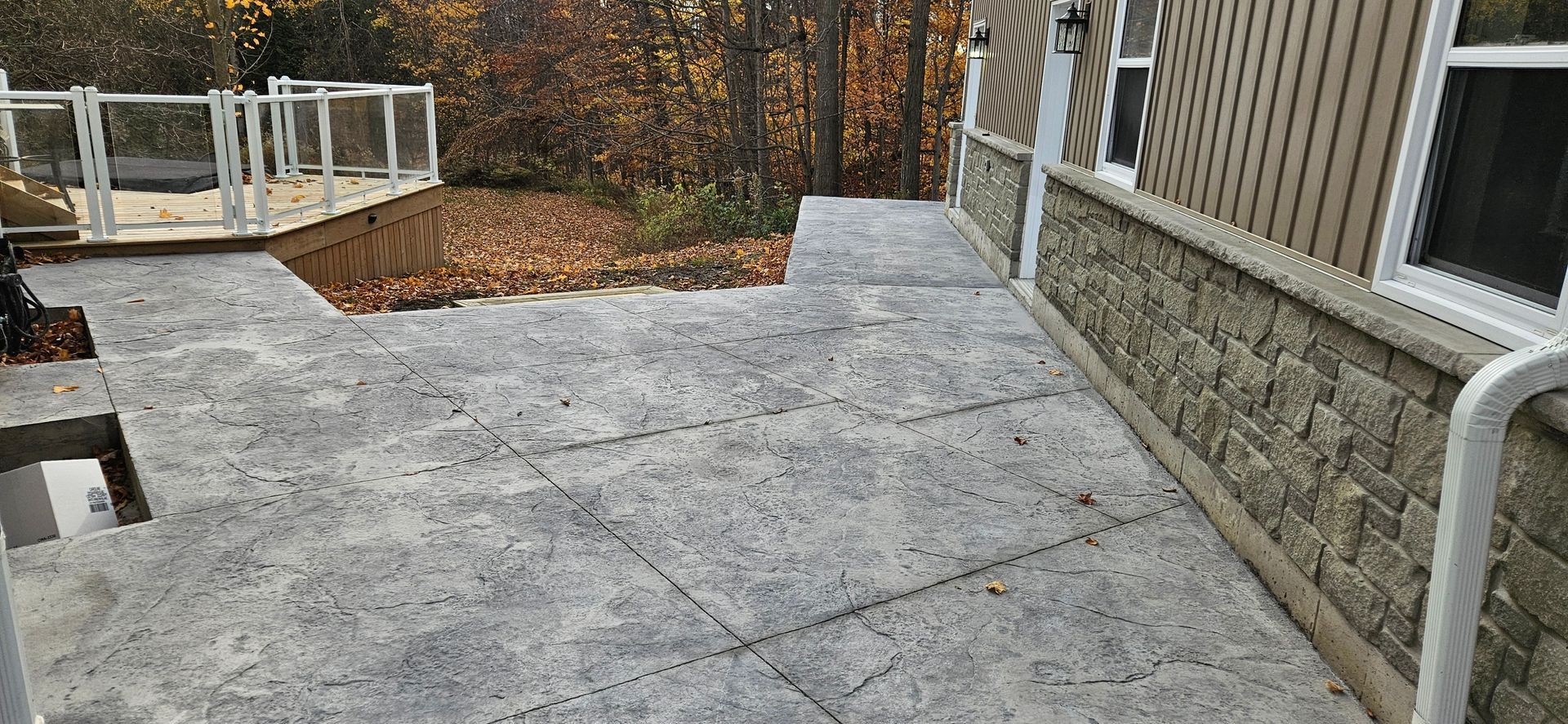 A patio with a table and chairs and umbrellas in front of a pool.