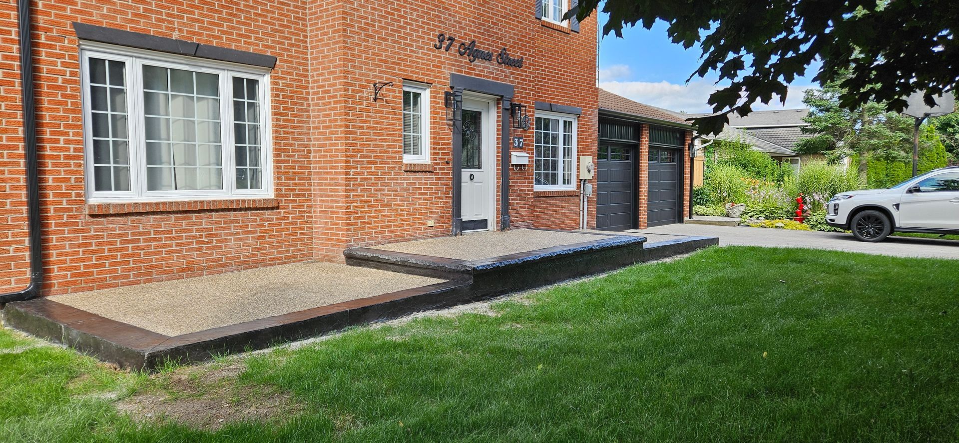 A brick house with a concrete walkway leading to the front door.