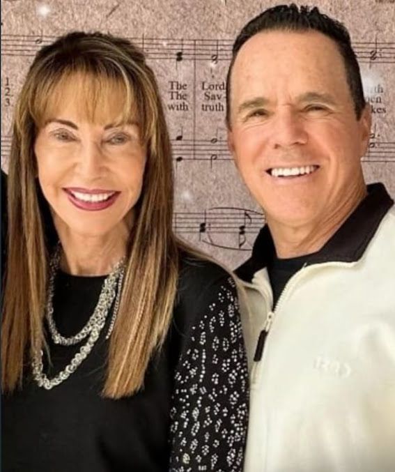 A man and a woman are posing for a picture in front of sheet music