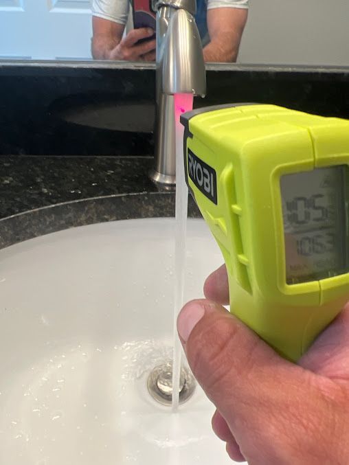 A person is measuring the temperature of the water in a sink