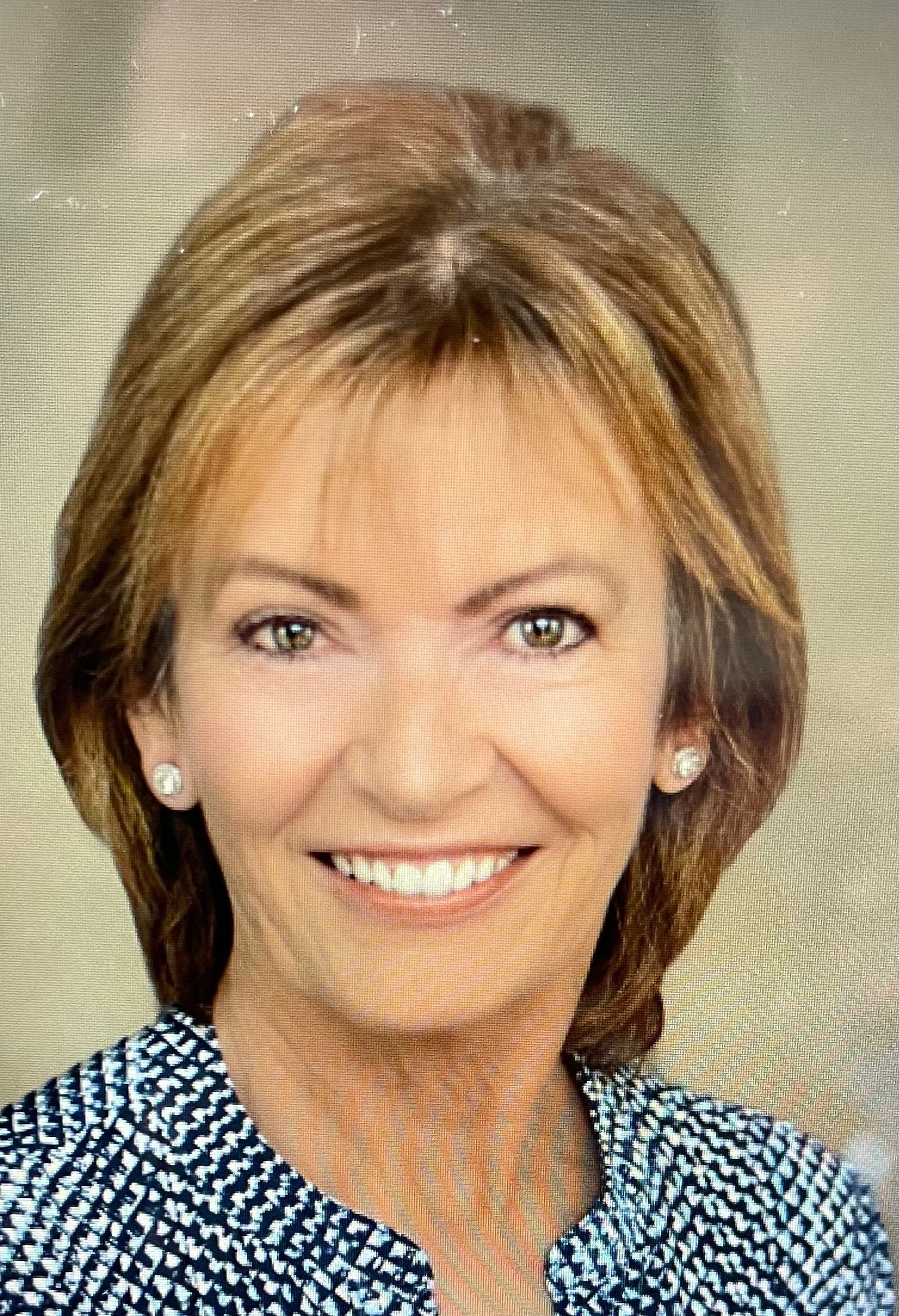 A close up of a woman 's face smiling and wearing a blue shirt.