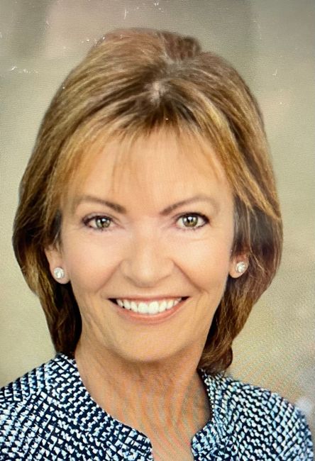 A close up of a woman 's face smiling and wearing a blue shirt.