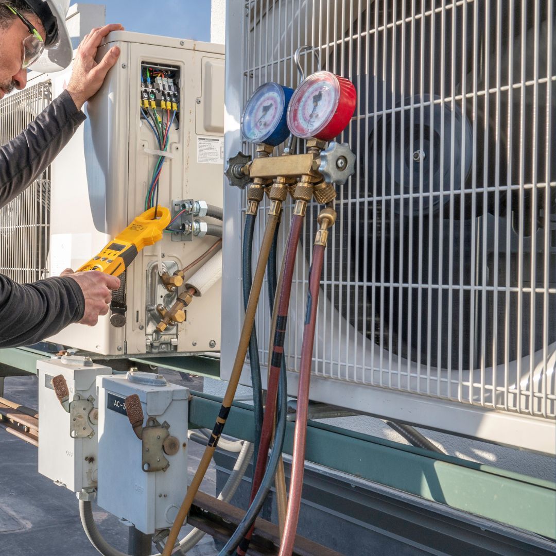 HVAC technician using gauges on an air conditioning unit; outdoors.