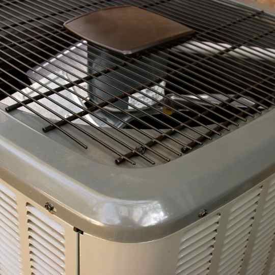 Air conditioner unit, gray metal, top grille with a dark-colored object on it.