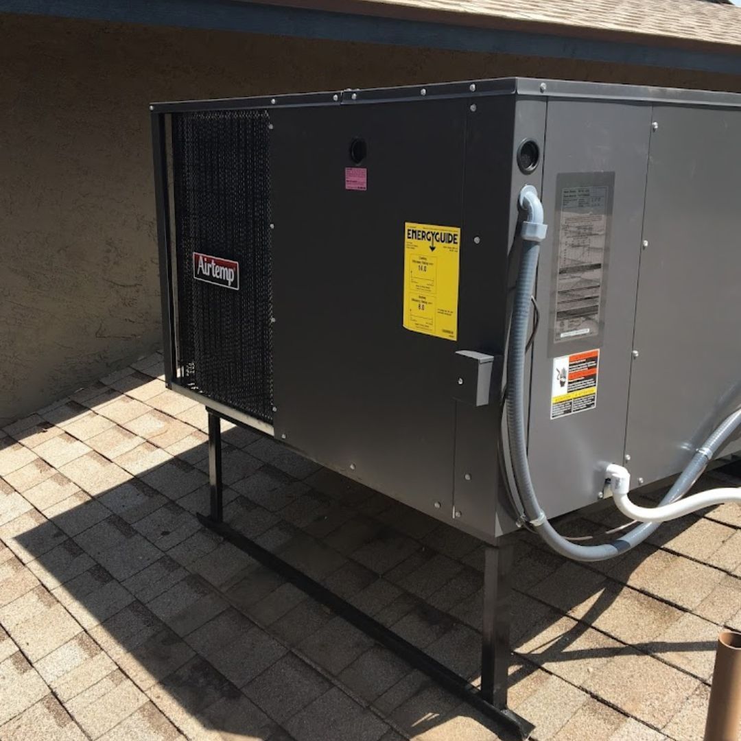Gray HVAC unit on a rooftop, supported by black metal legs.