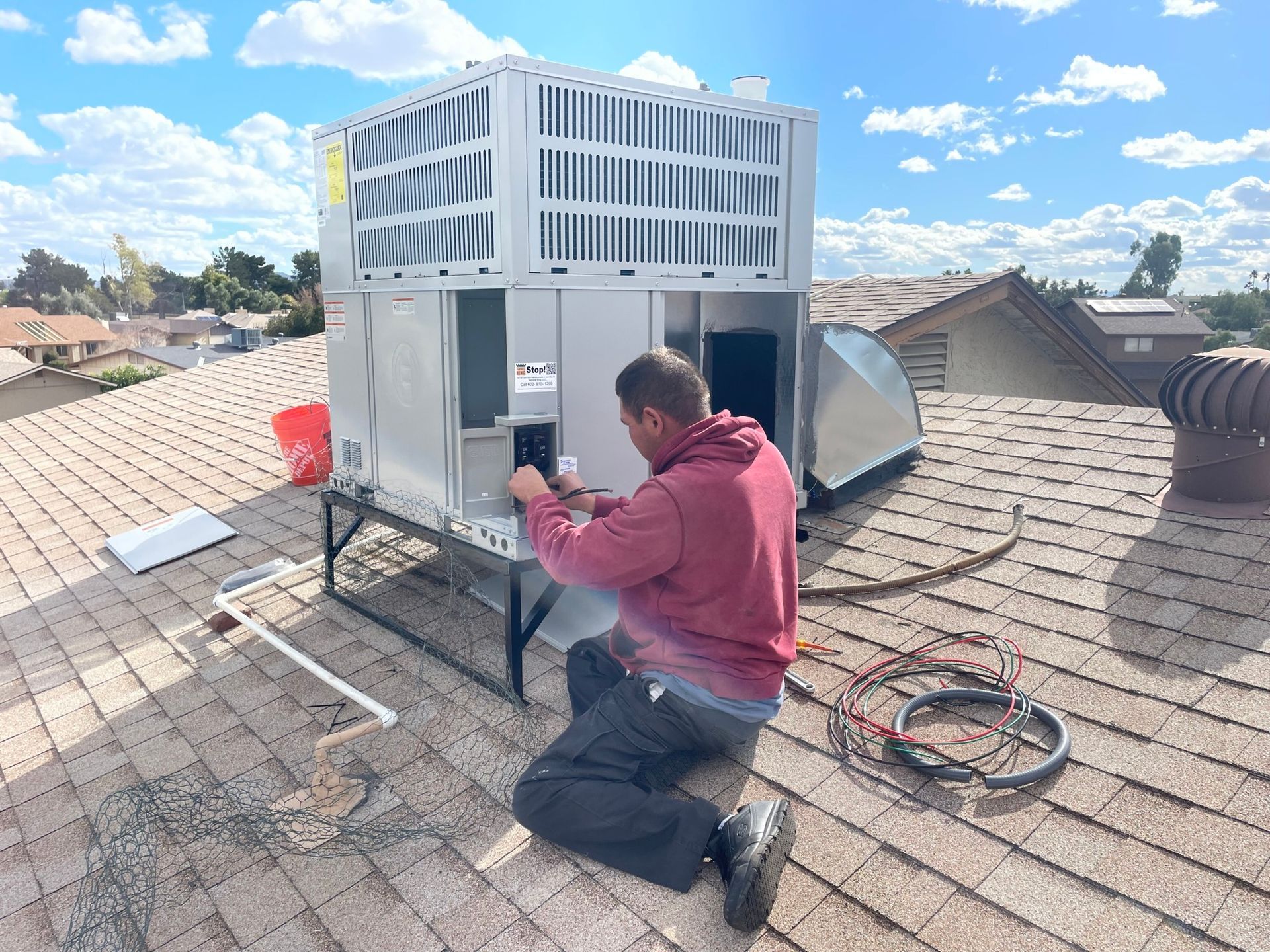 HVAC technician working on rooftop unit, installing ductwork. Sunny day.