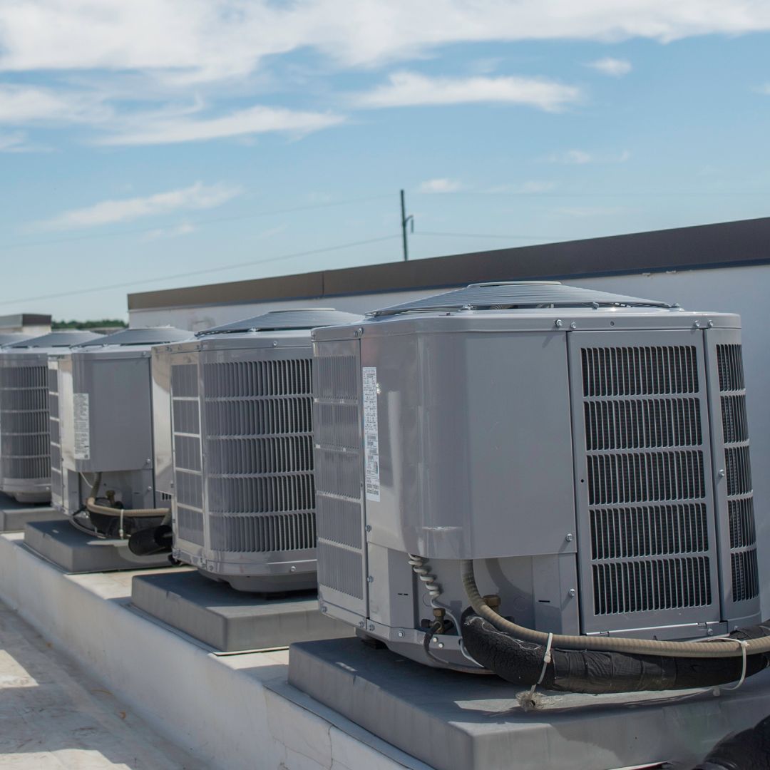 Row of rooftop air conditioning units on a building with a blue sky.
