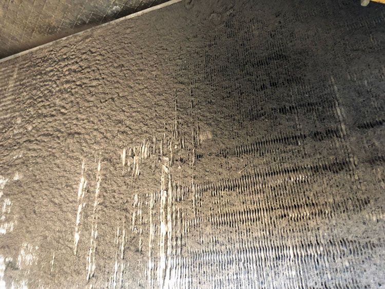 A heavily soiled air conditioning coil, coated in thick dust and debris.