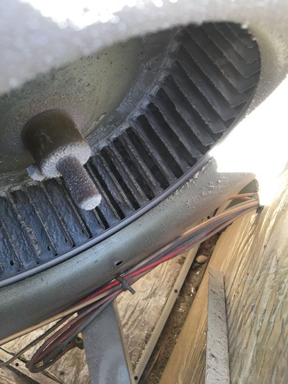 Ice buildup on the fan blades and shaft of an air conditioner unit.