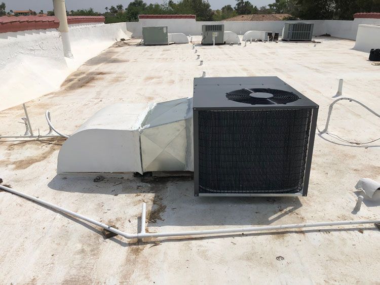 HVAC unit on a white roof, with ductwork and a condenser, under a sunny sky.