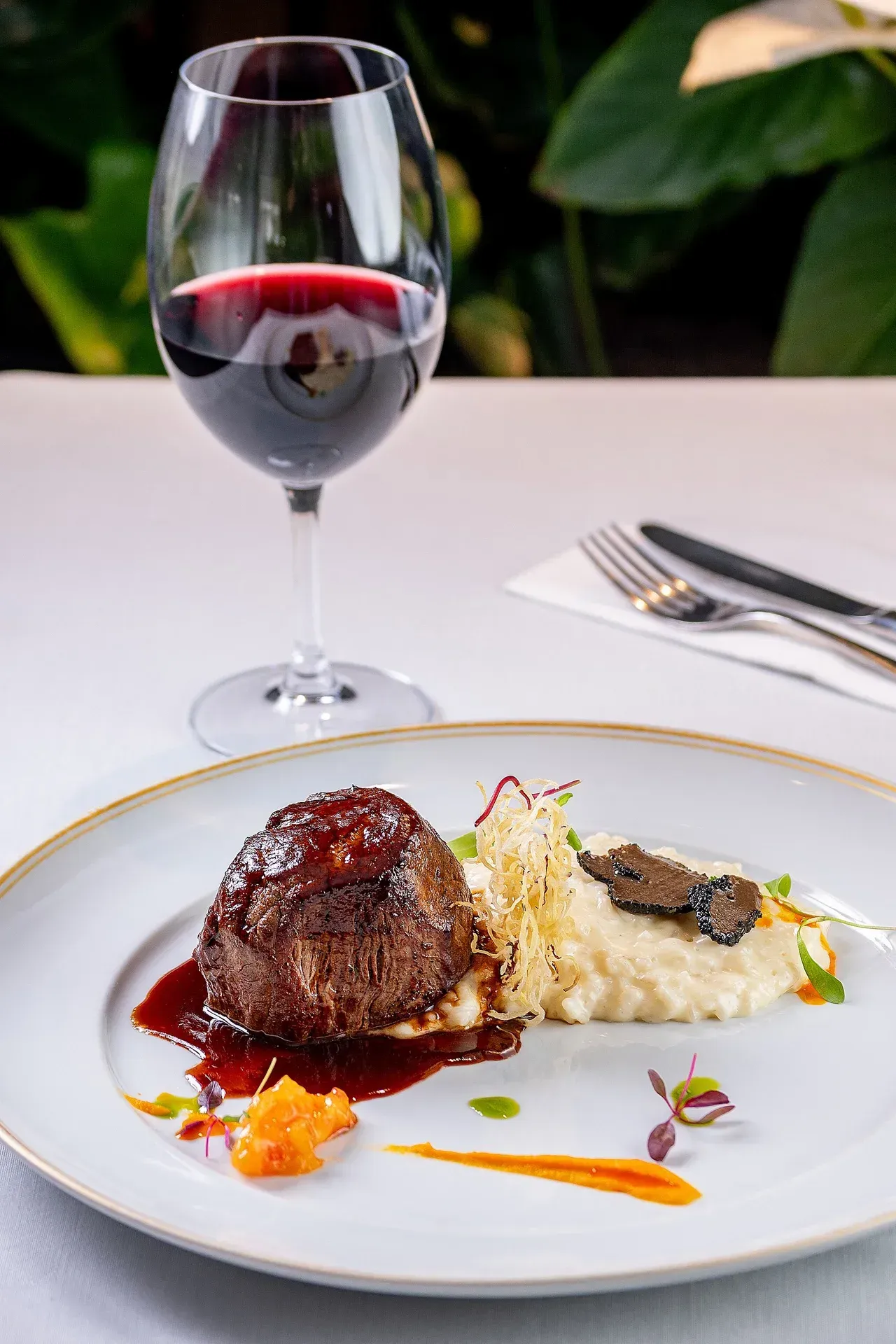Um prato de comida e uma taça de vinho sobre a mesa.