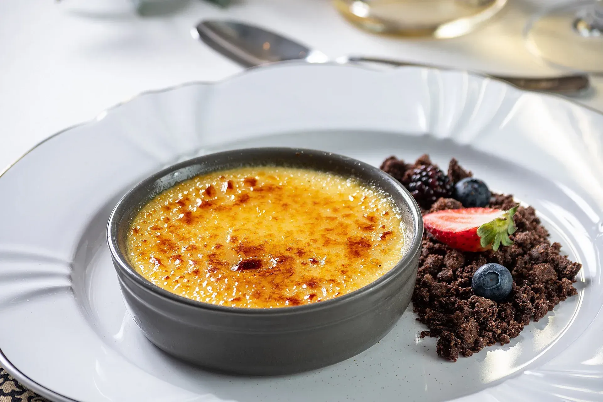 Um prato branco coberto com uma tigela de sobremesa e frutas vermelhas