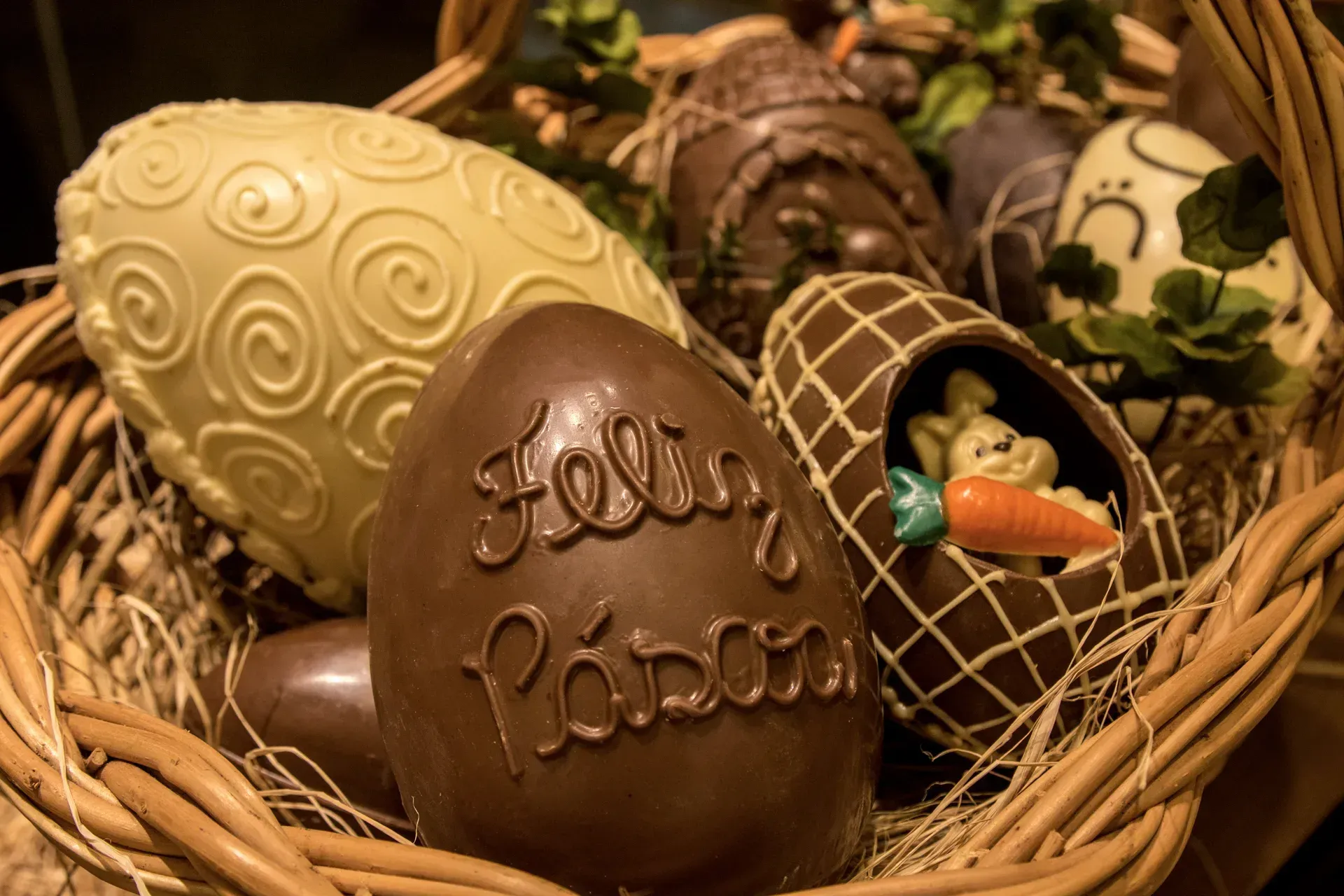 Uma cesta de vime cheia de ovos de páscoa de chocolate.