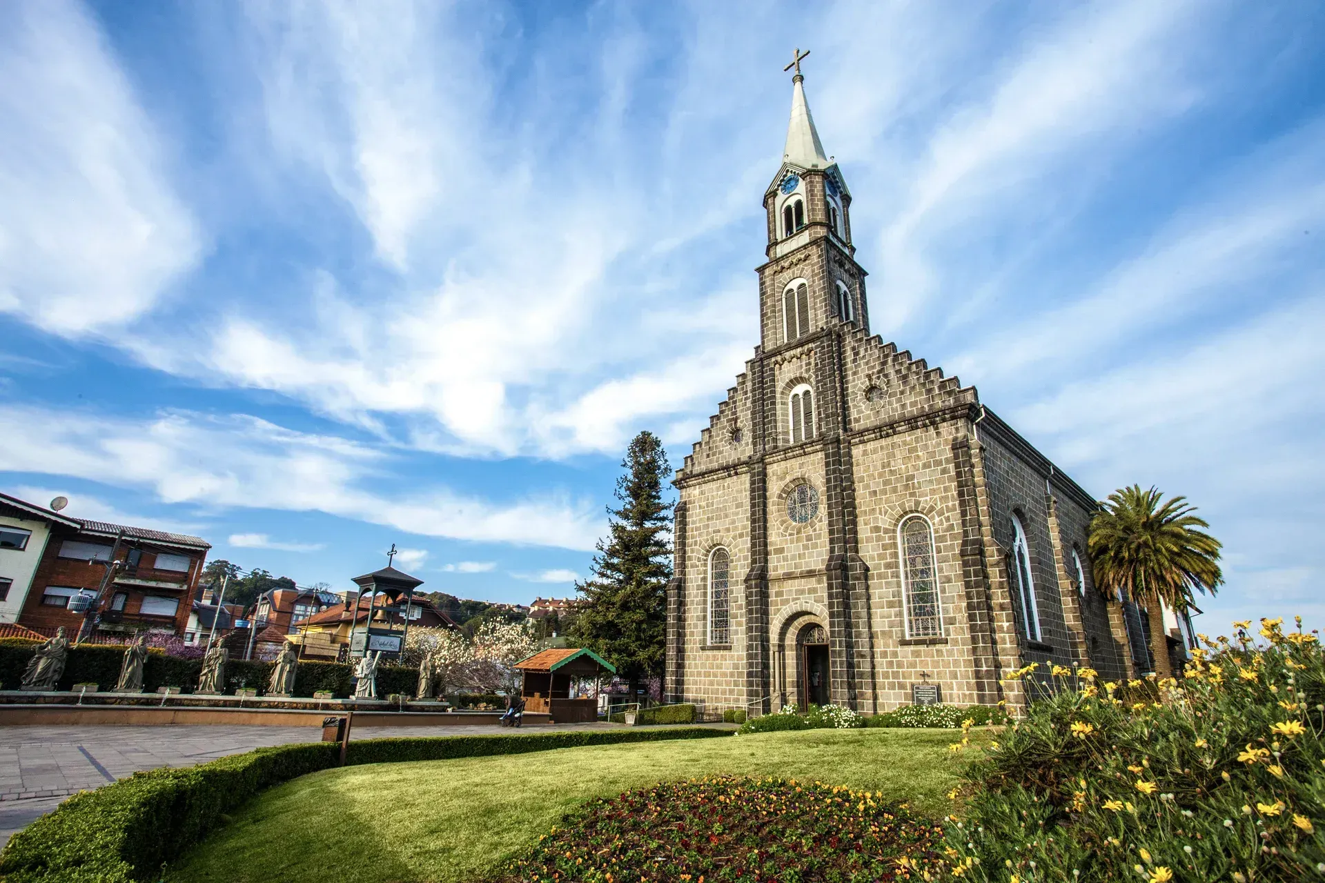 Uma grande igreja de pedra com um campanário e uma cruz no topo.