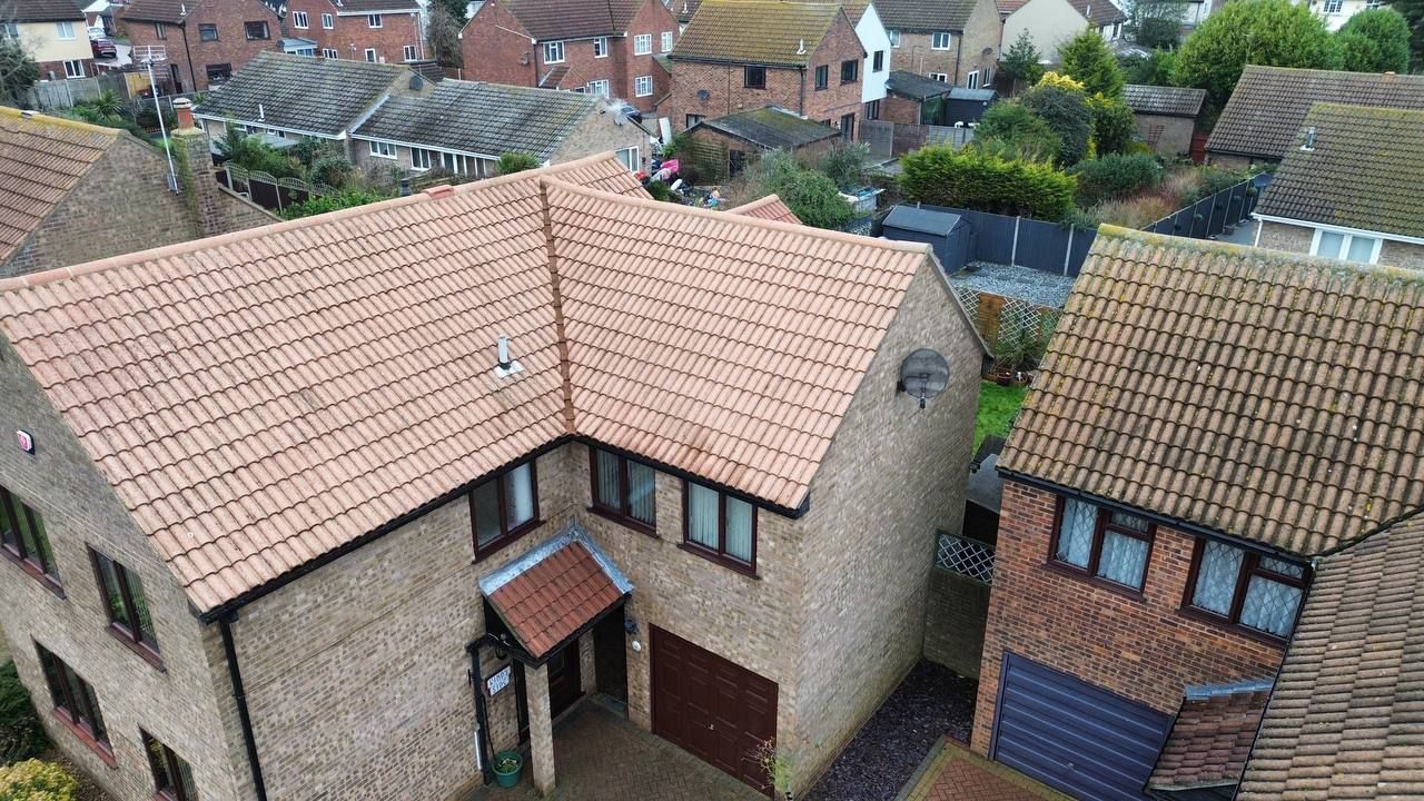 Overhead view of a two-story brick house with a brown tile roof, set in a residential neighborhood.