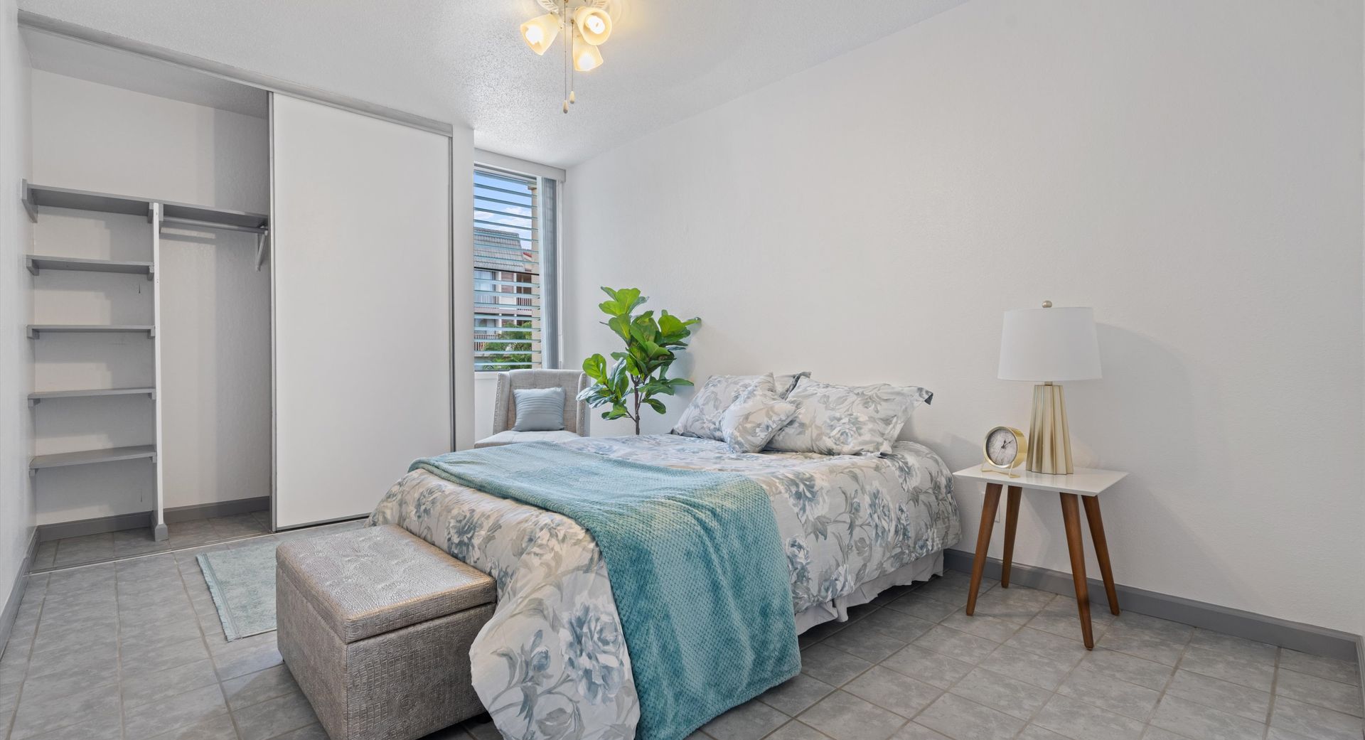 A bedroom with a bed , nightstand , lamp and closet.
