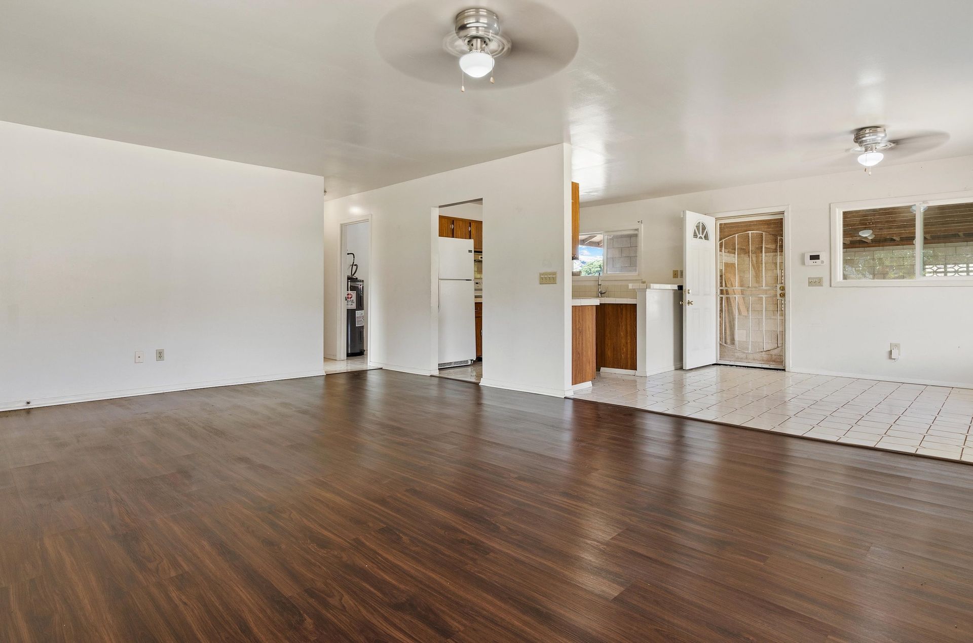 An empty living room with hardwood floors and a ceiling fan.