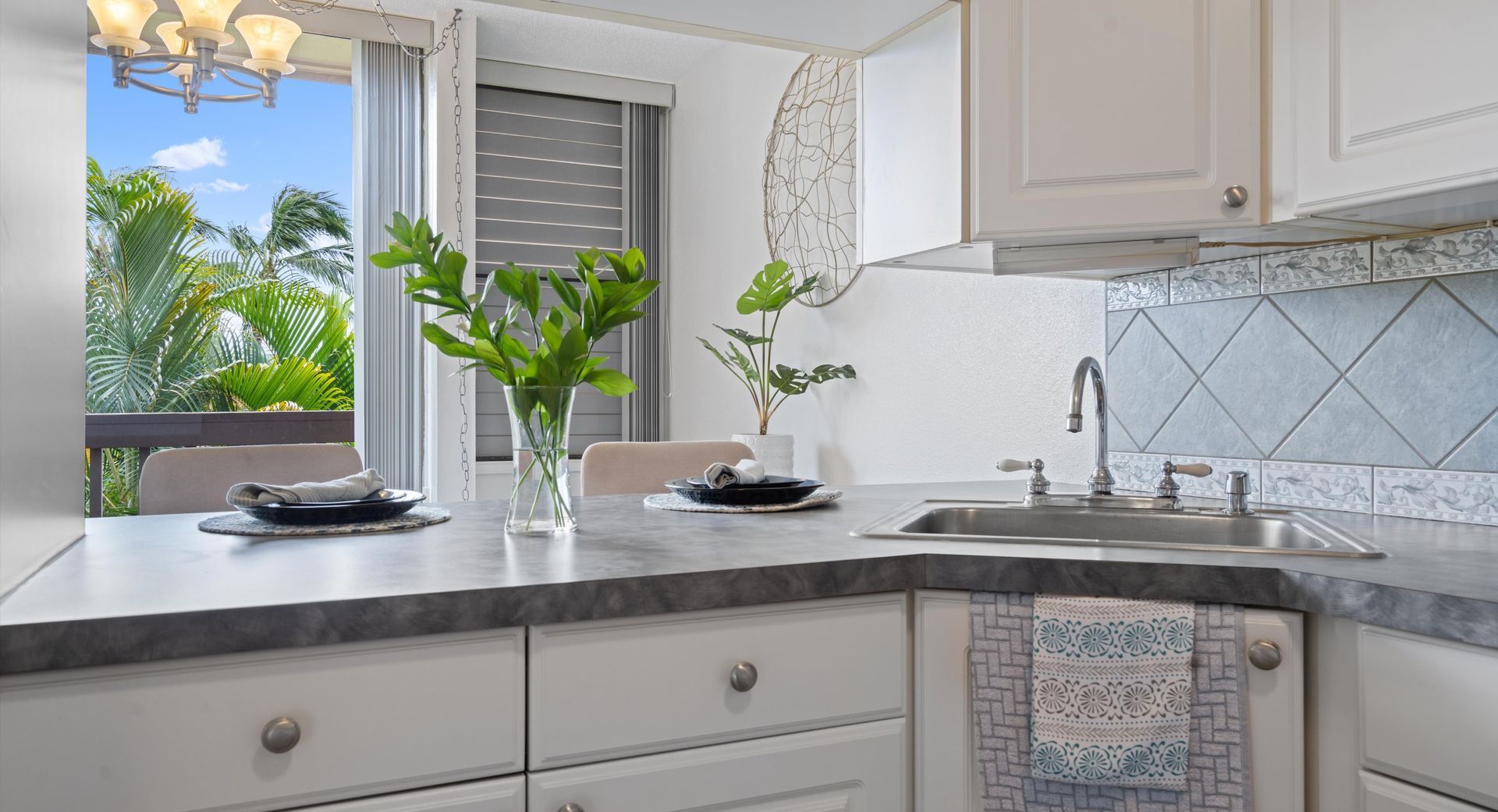 A kitchen with white cabinets , a sink , and a window.