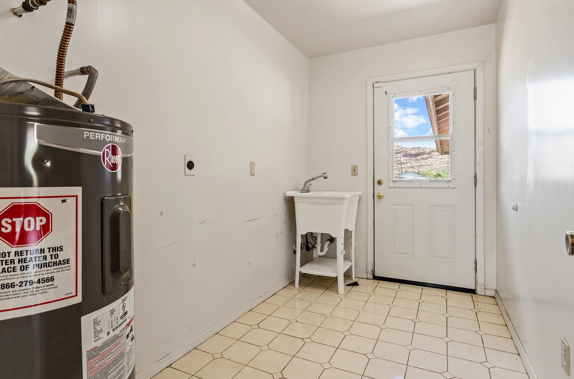 A laundry room with a water heater and a sink.