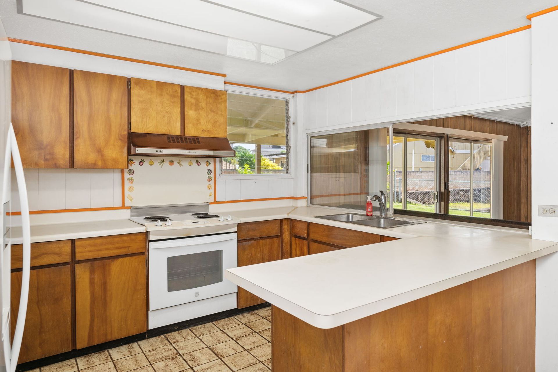 A kitchen with wooden cabinets , white appliances , and a large island.