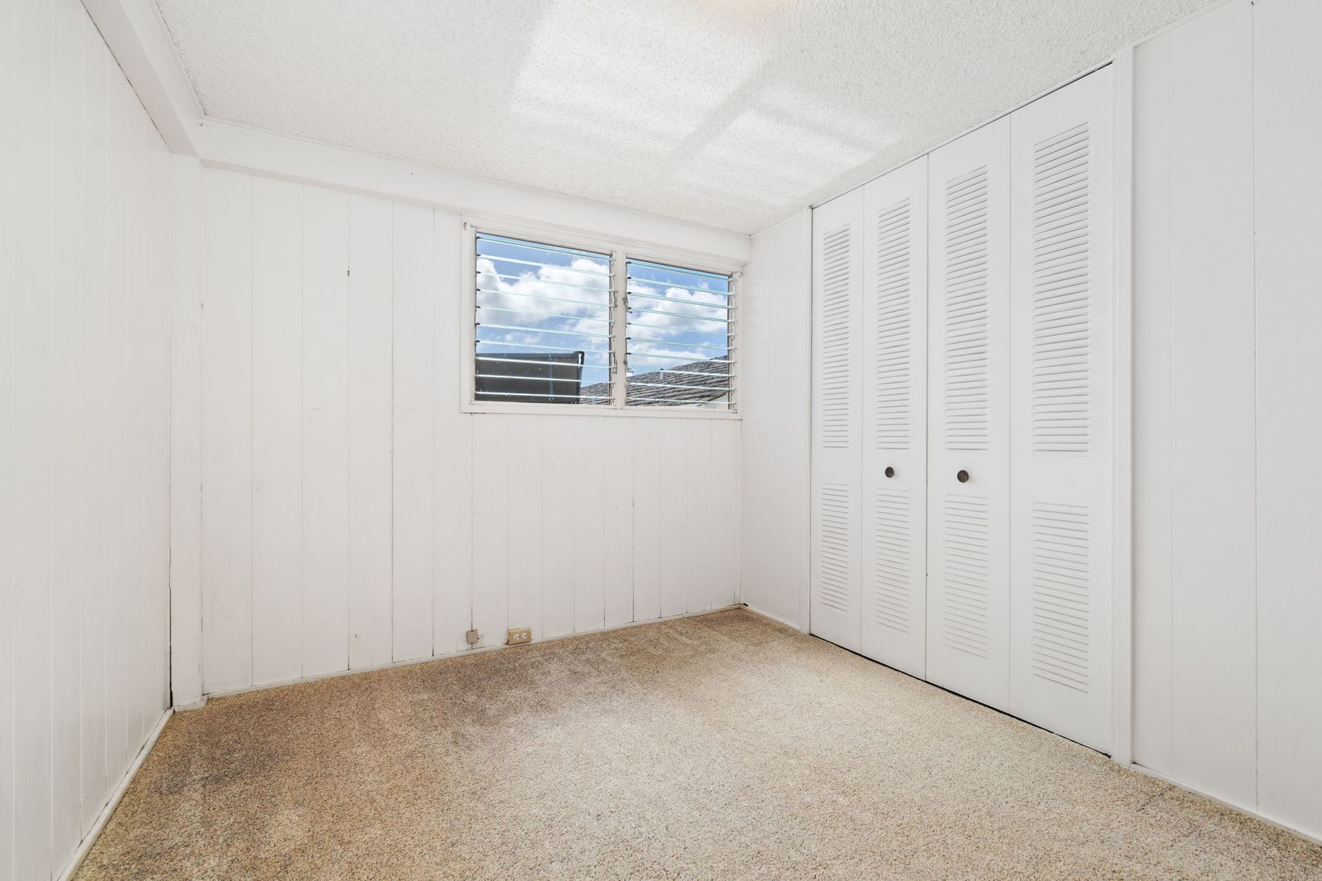 An empty bedroom with white walls and a window.