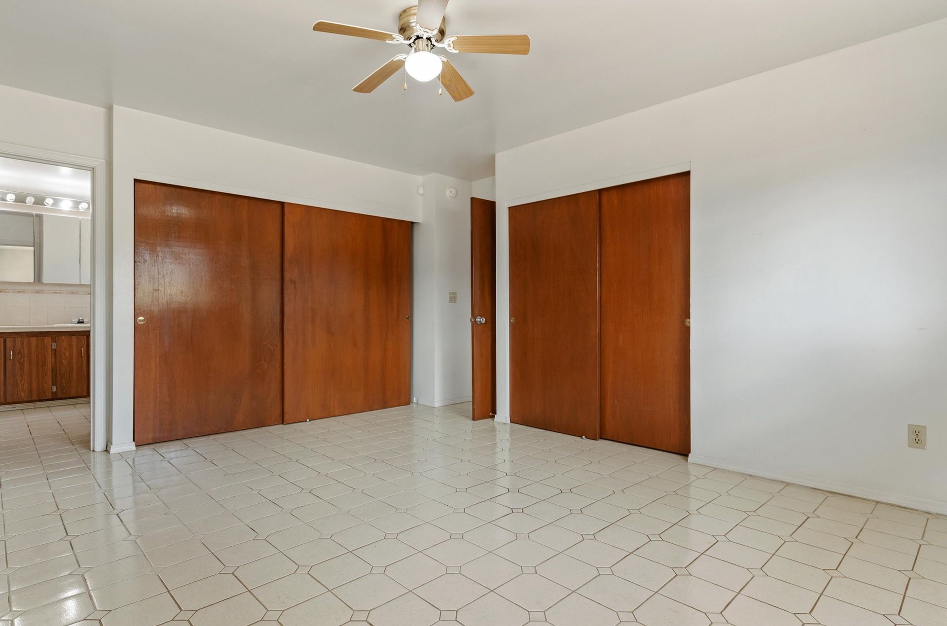 An empty room with sliding doors and a ceiling fan