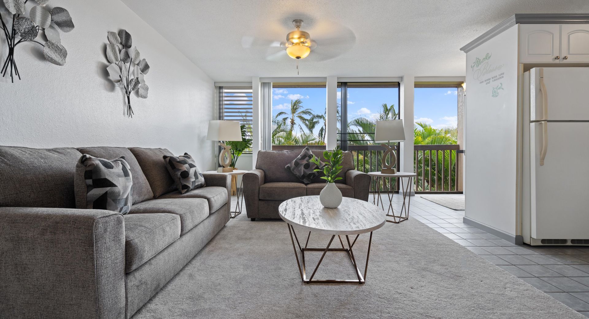 A living room with a couch , chair , coffee table and ceiling fan.