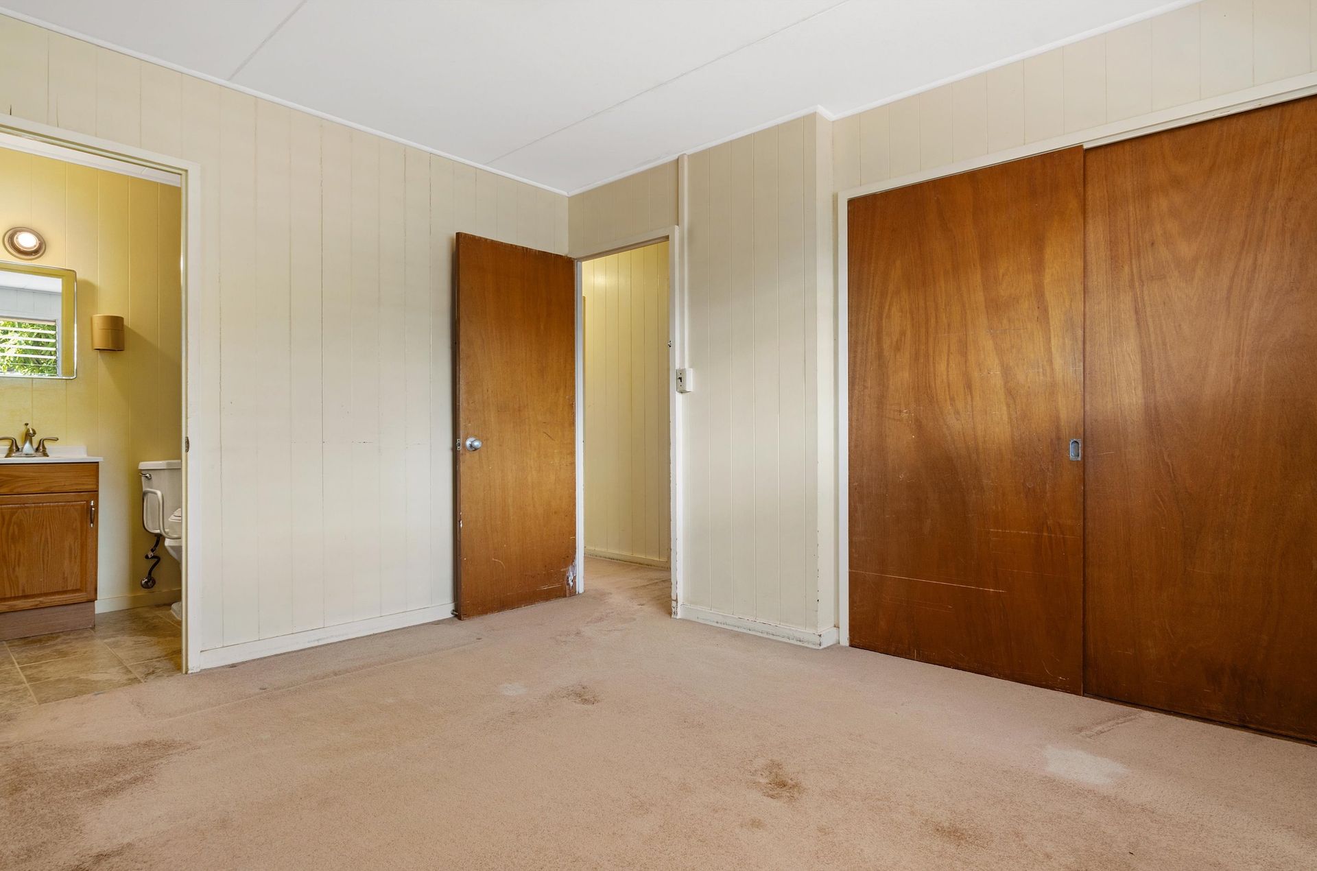 An empty bedroom with a toilet , sink and closet.
