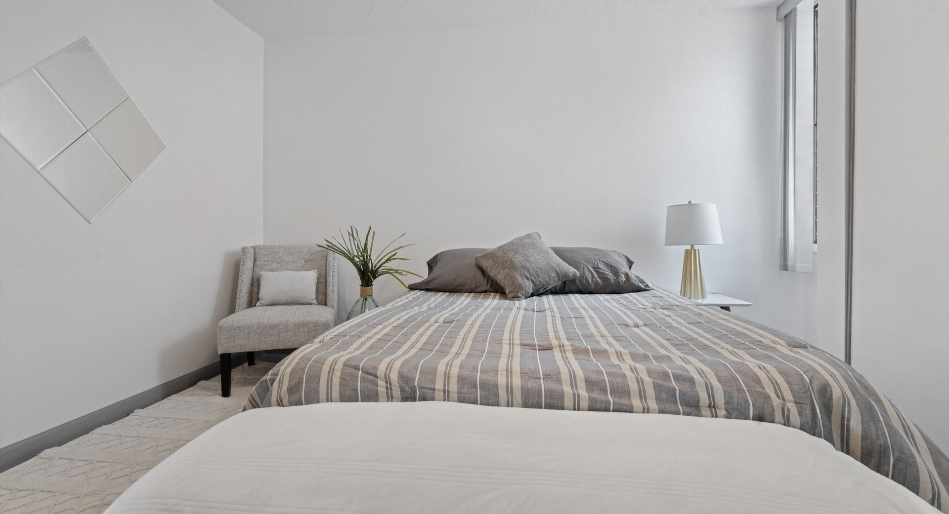 A bedroom with a bed , chair , lamp and mirror.