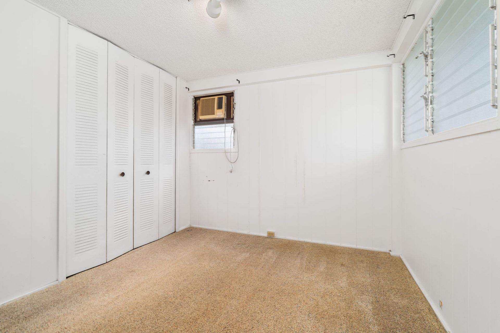 An empty bedroom with a window and a ceiling fan