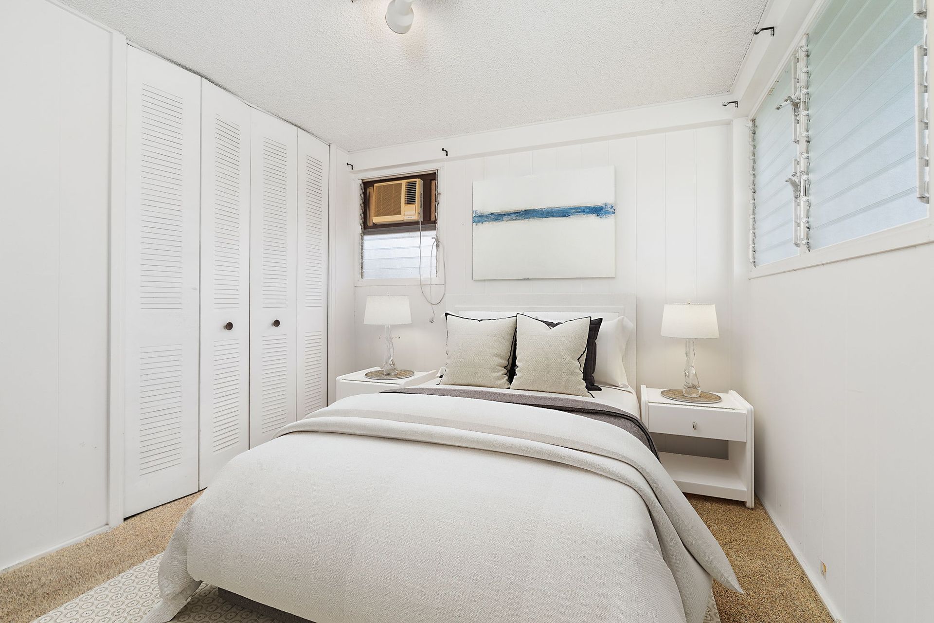 A bedroom with a bed , nightstand , lamps and a window.