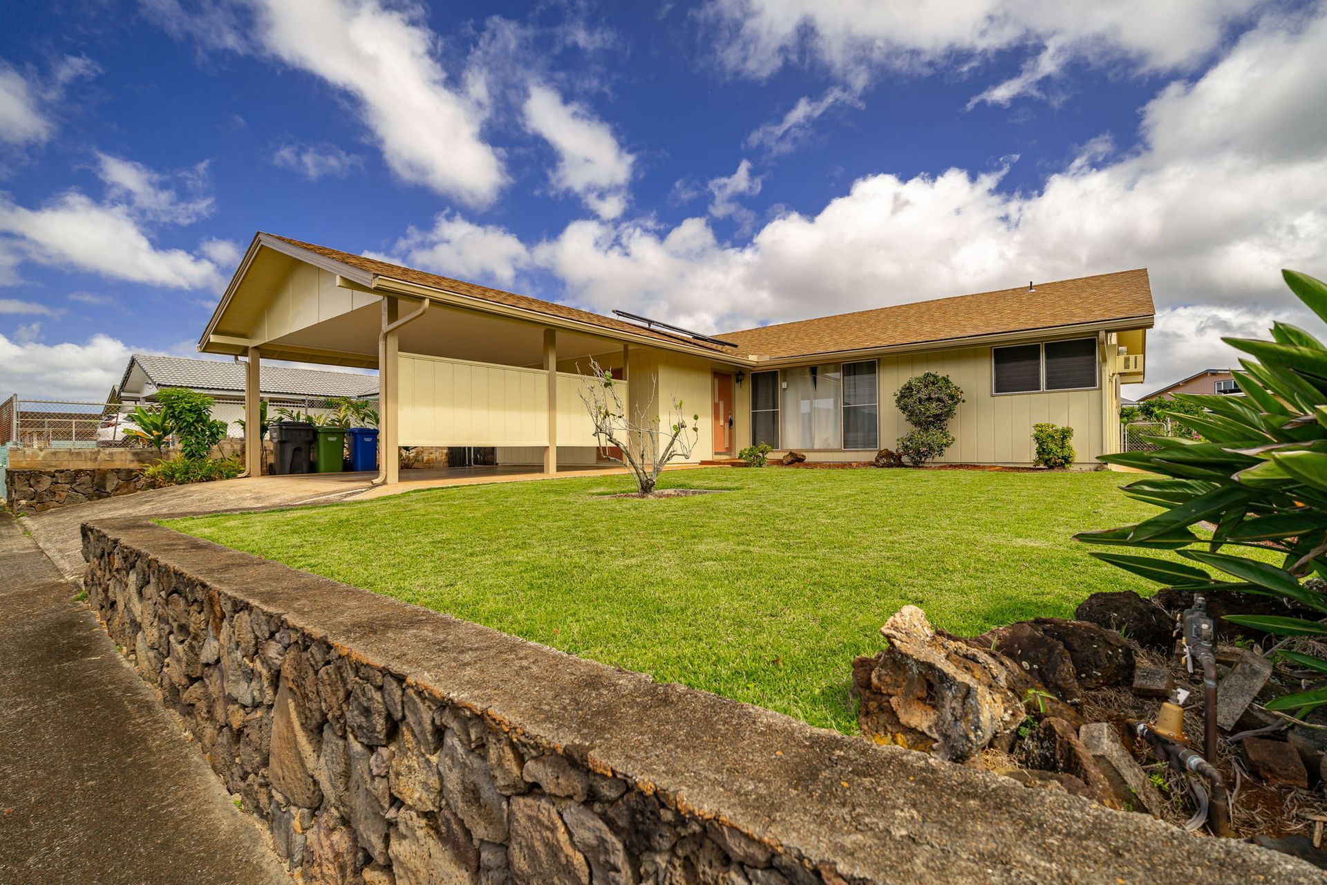 A house with a large lawn and a stone wall in front of it