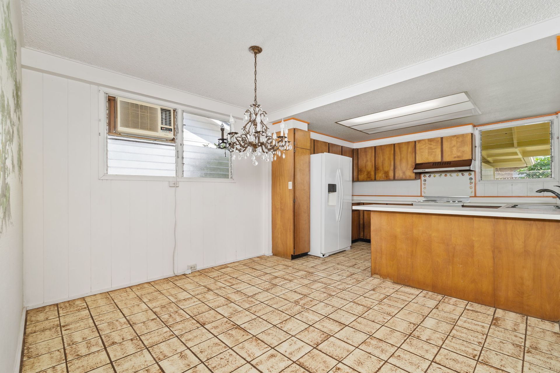 An empty kitchen with a chandelier hanging from the ceiling.