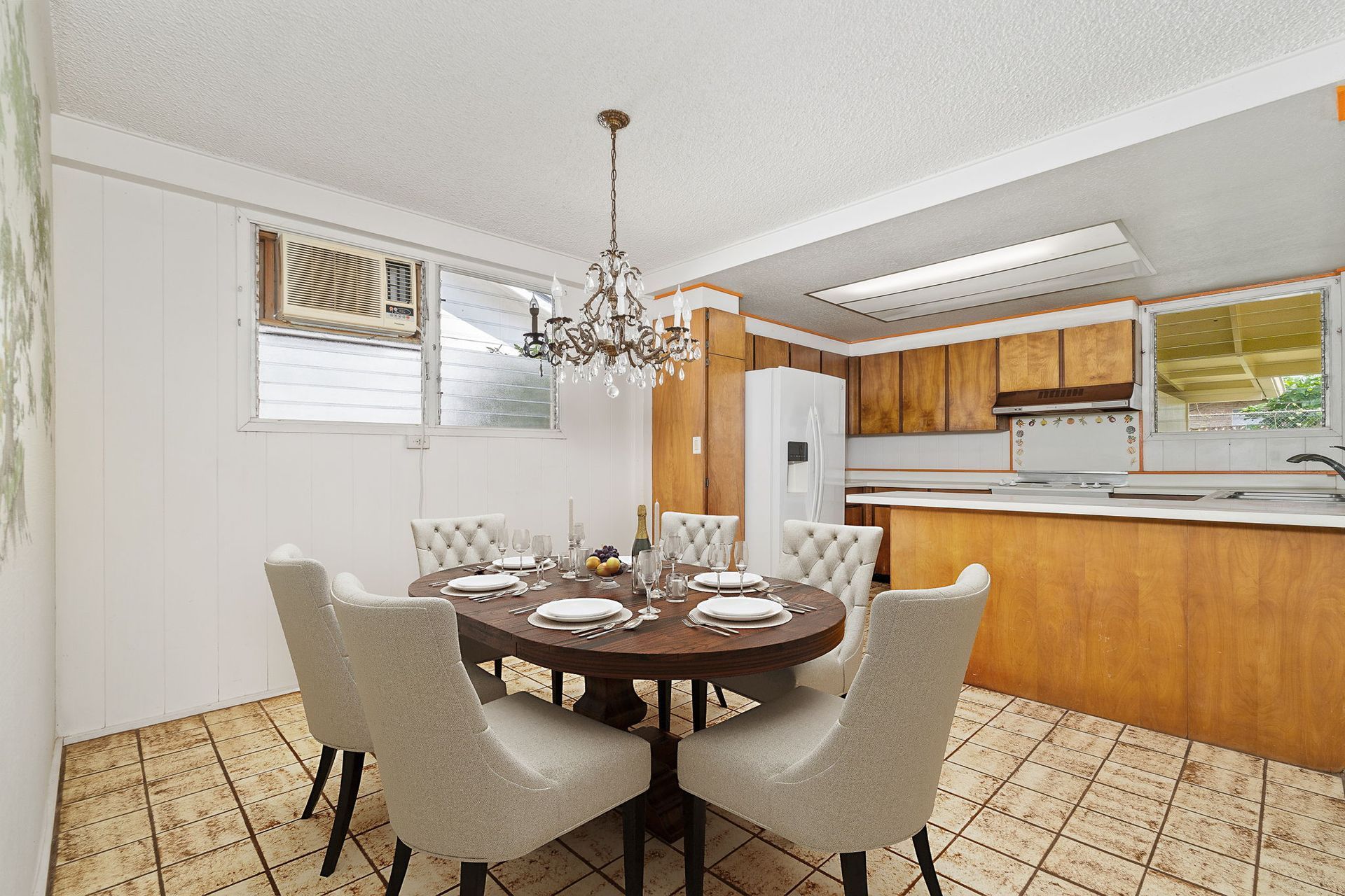 A dining room with a round table and chairs and a chandelier.