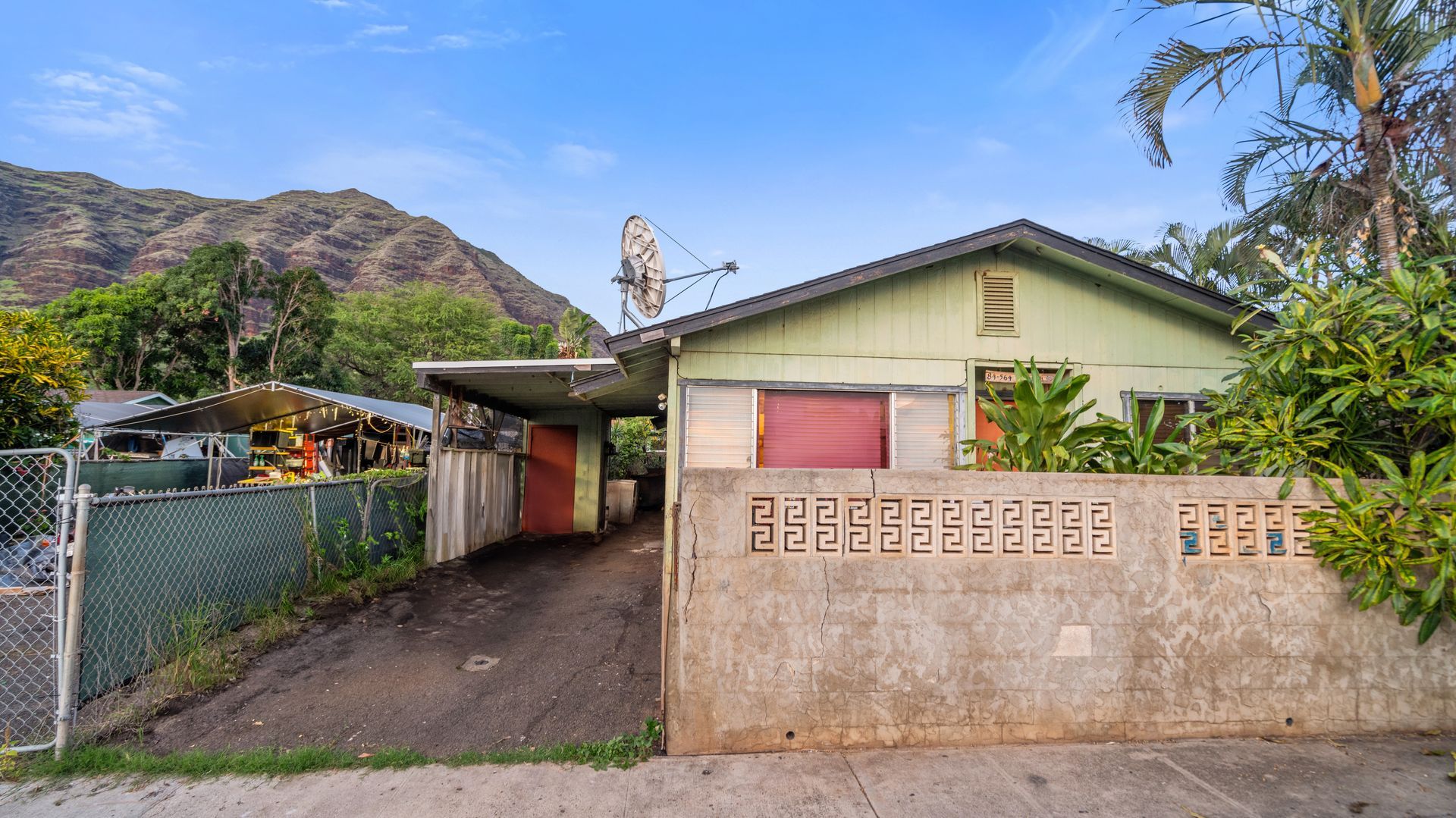 A green house with a fence and mountains in the background