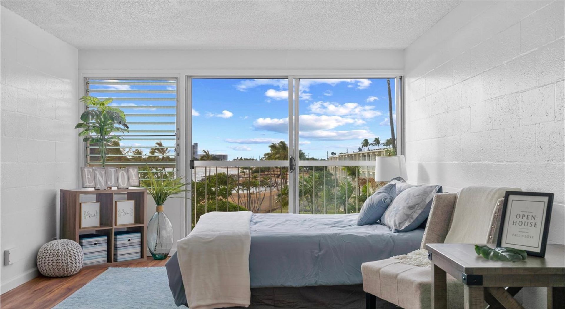 A bedroom with a bed , chair , table and sliding glass doors.