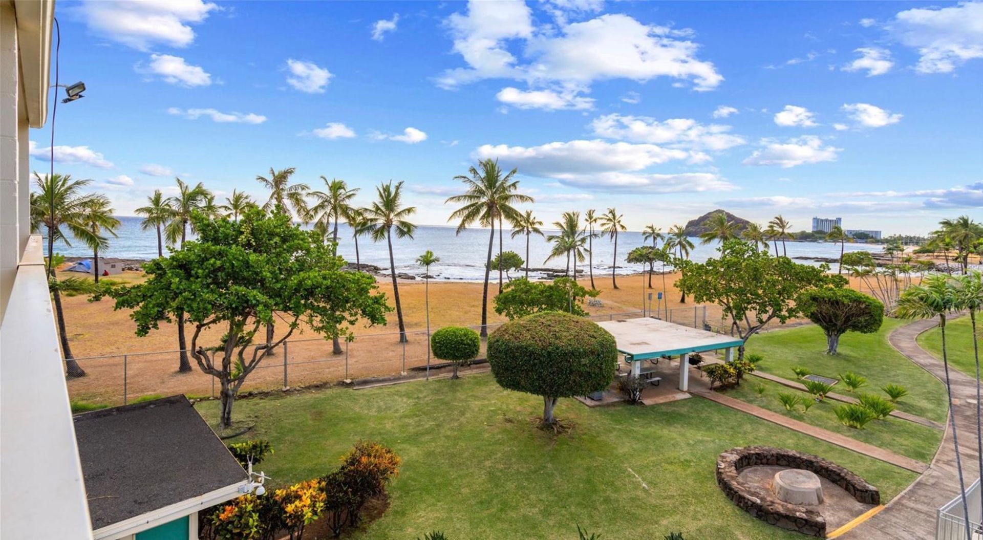 An aerial view of a beach with palm trees and a house in the foreground.