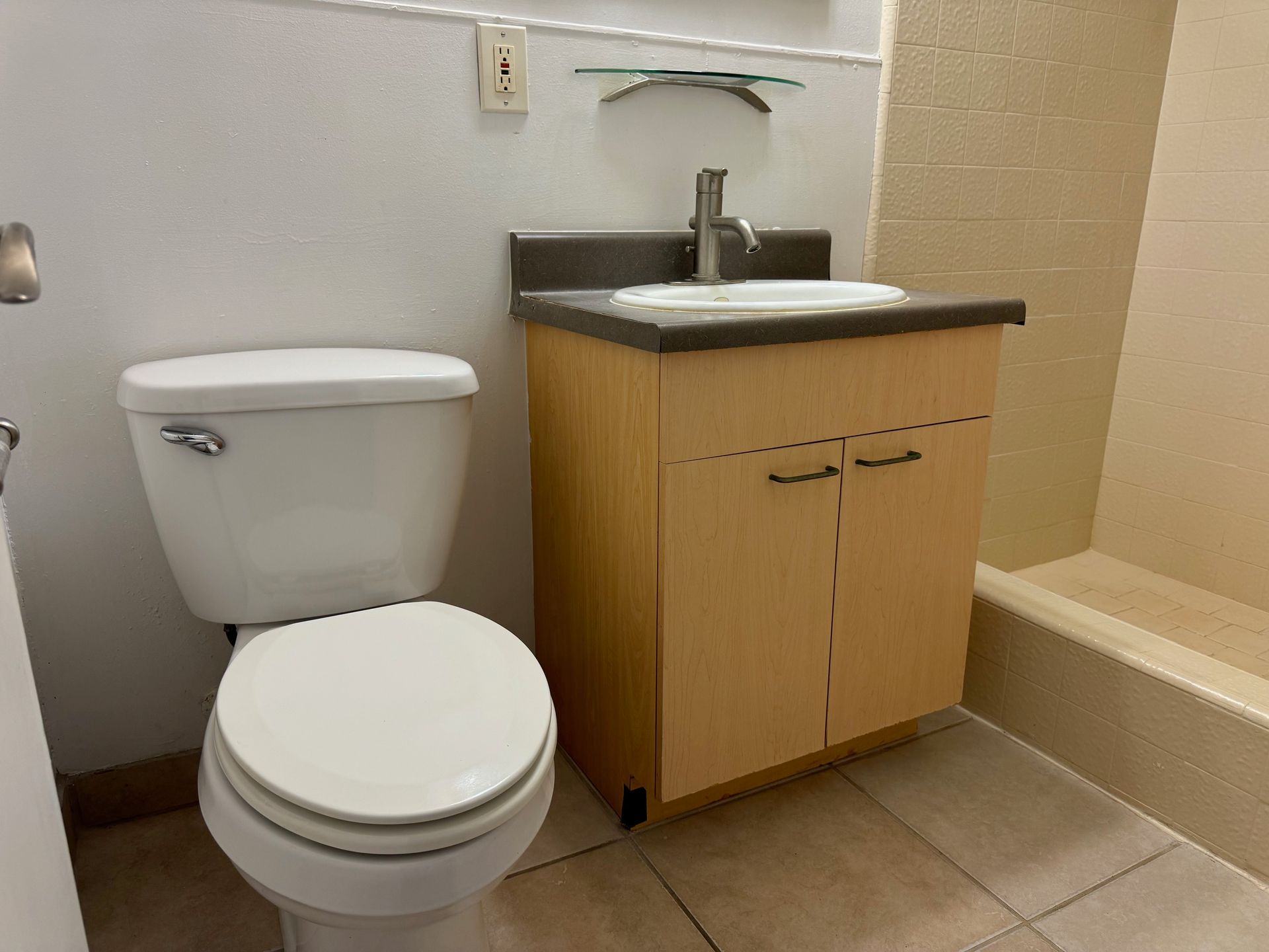 A bathroom with a toilet , sink and shower.