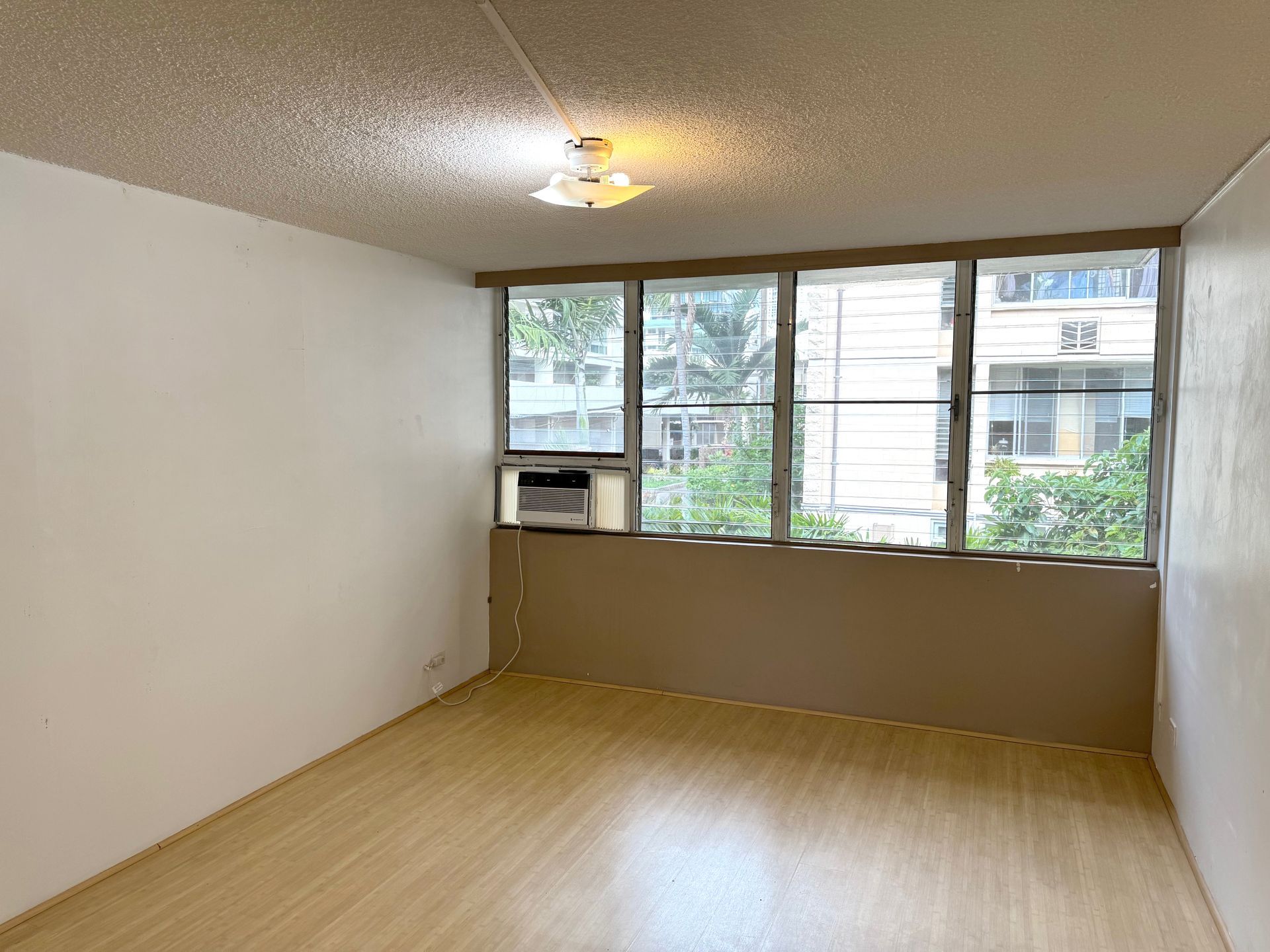 An empty living room with hardwood floors and a window.