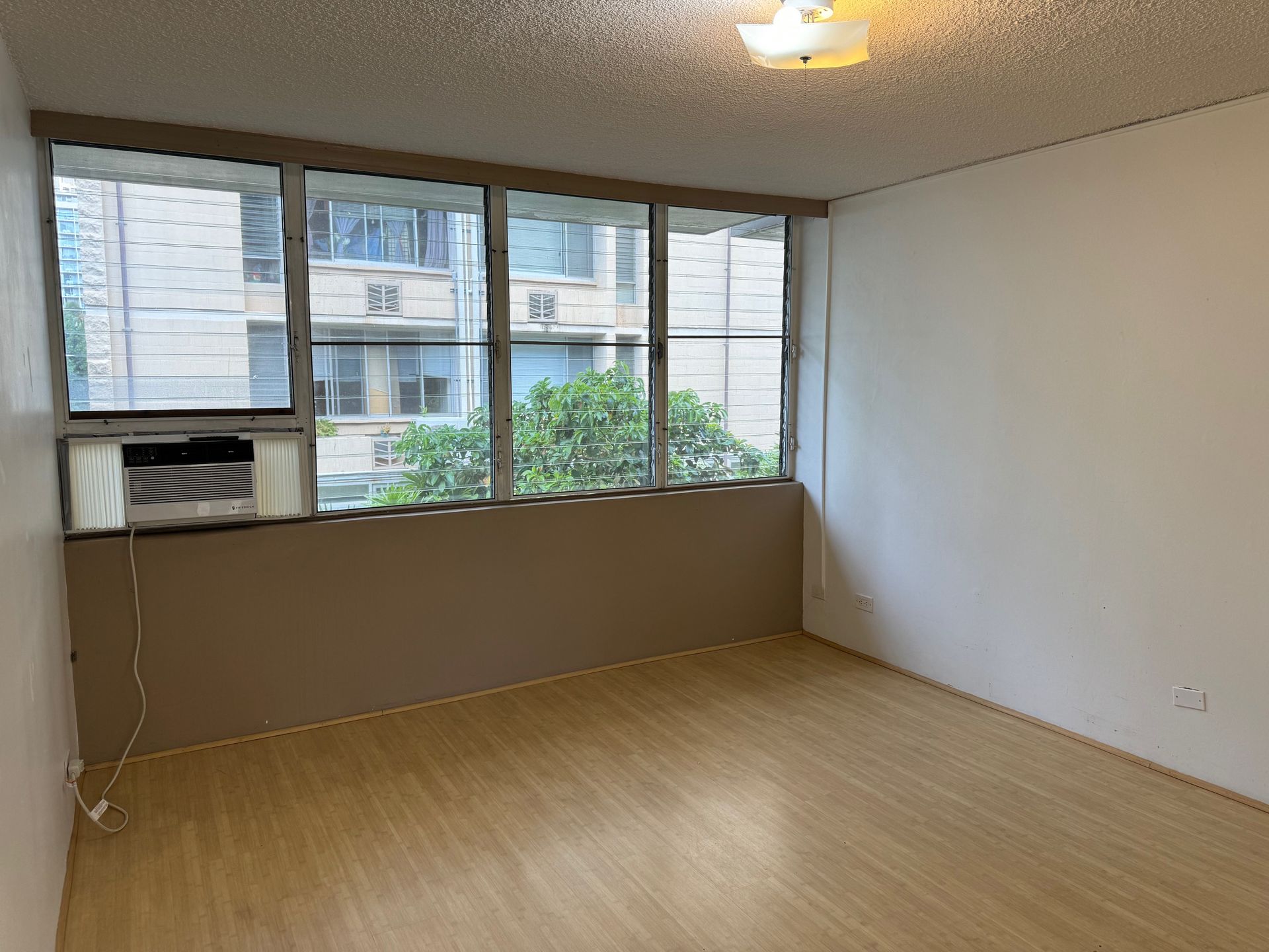 An empty room with hardwood floors and a large window