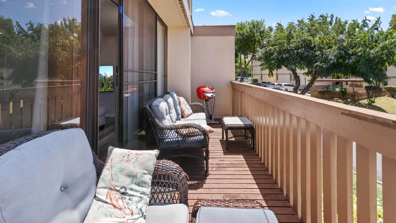 A balcony with a couch , chairs , and a grill.