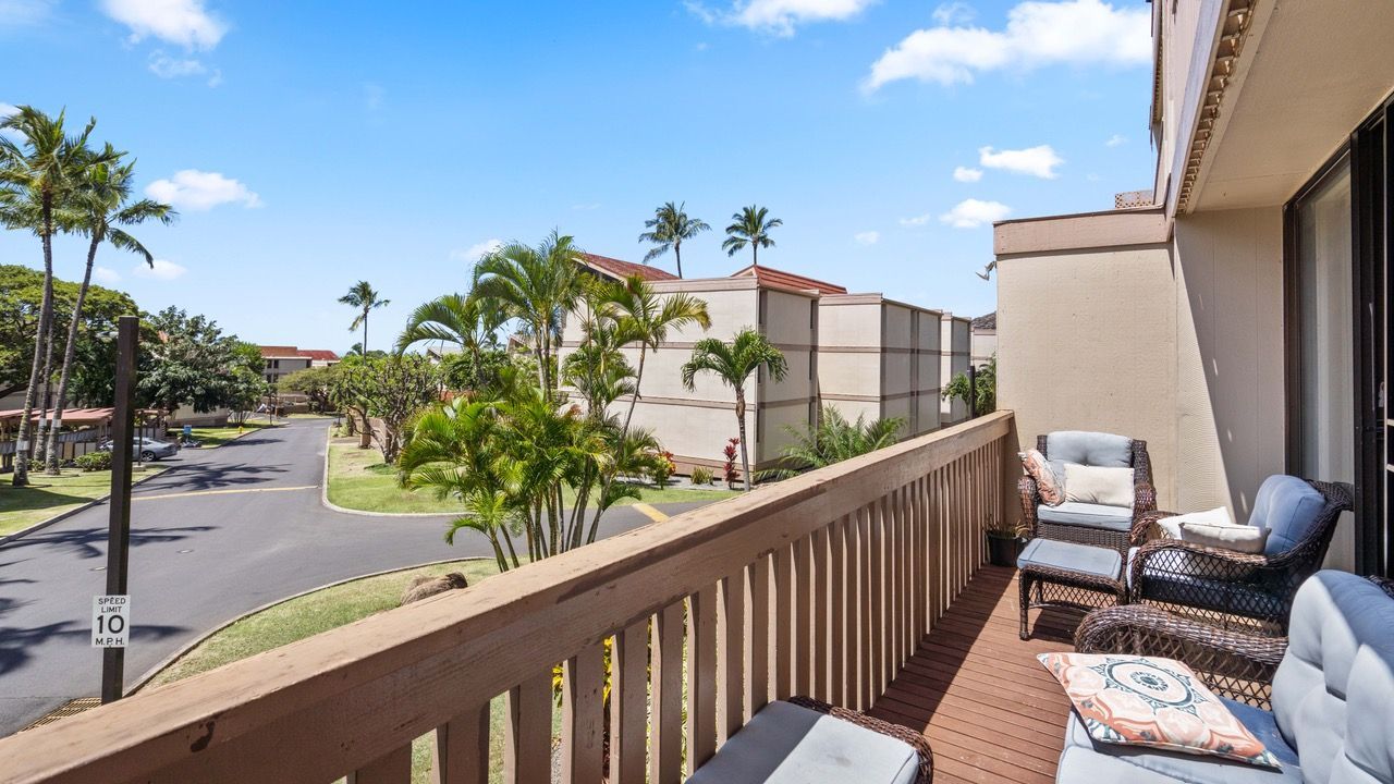 A balcony with a view of a street and palm trees.