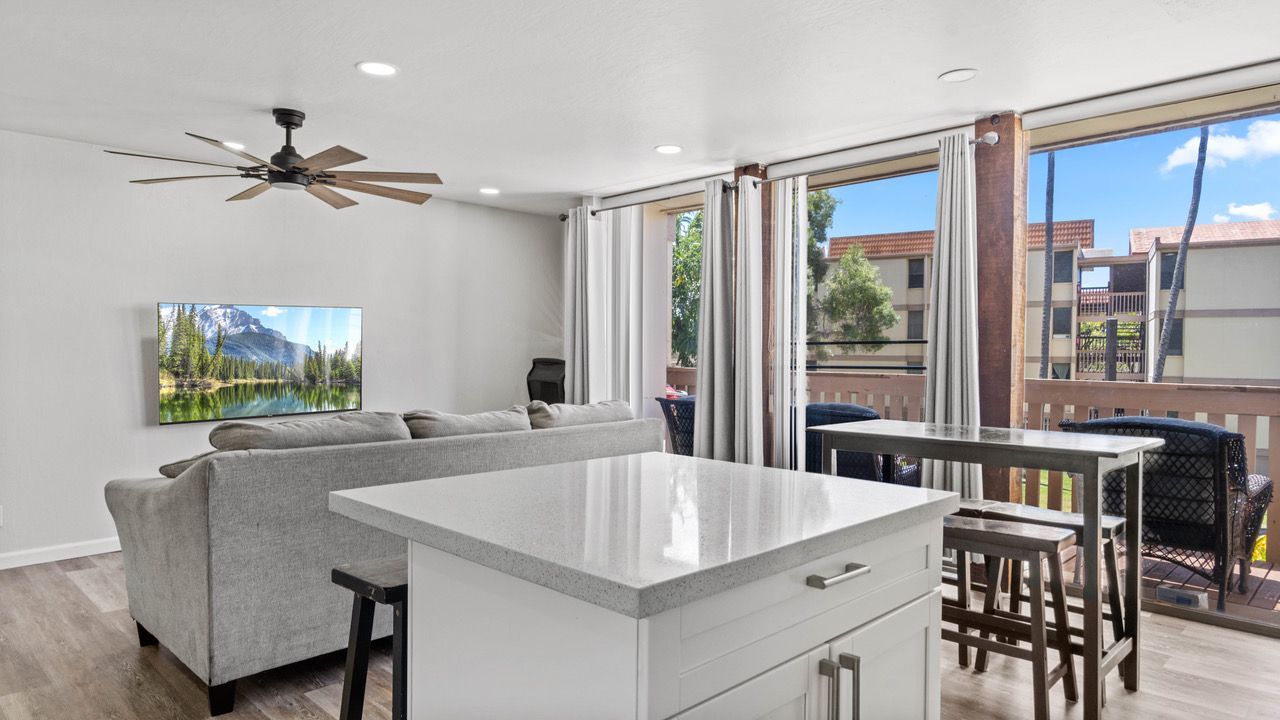 A living room with a couch , table , chairs and a ceiling fan.