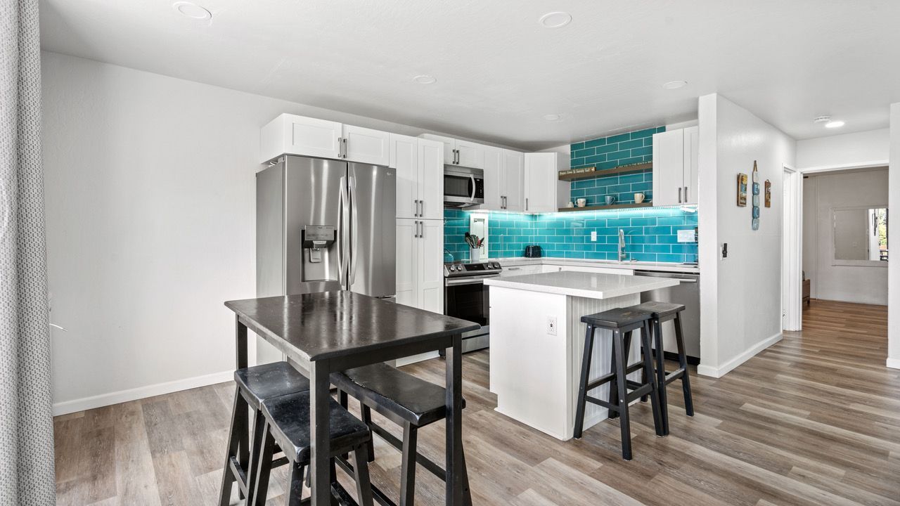 A kitchen with a table and stools and a refrigerator.