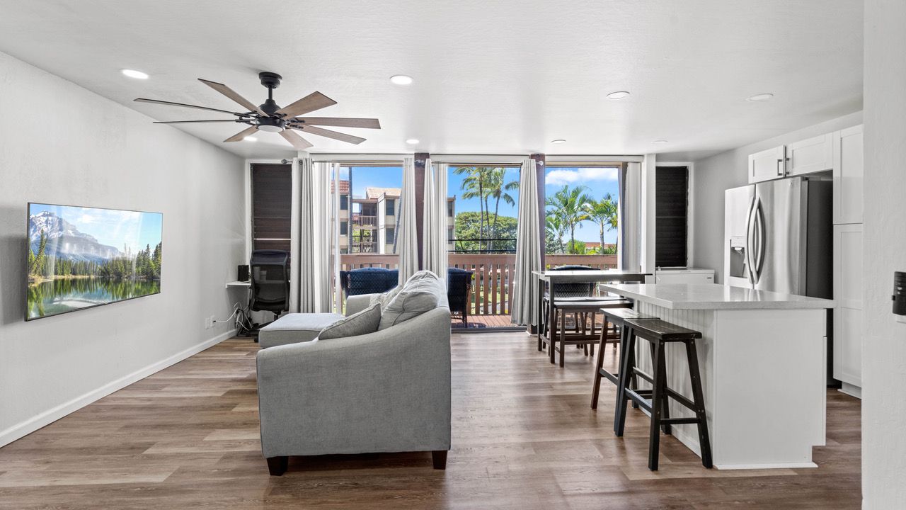 A living room with a couch , television , and ceiling fan.