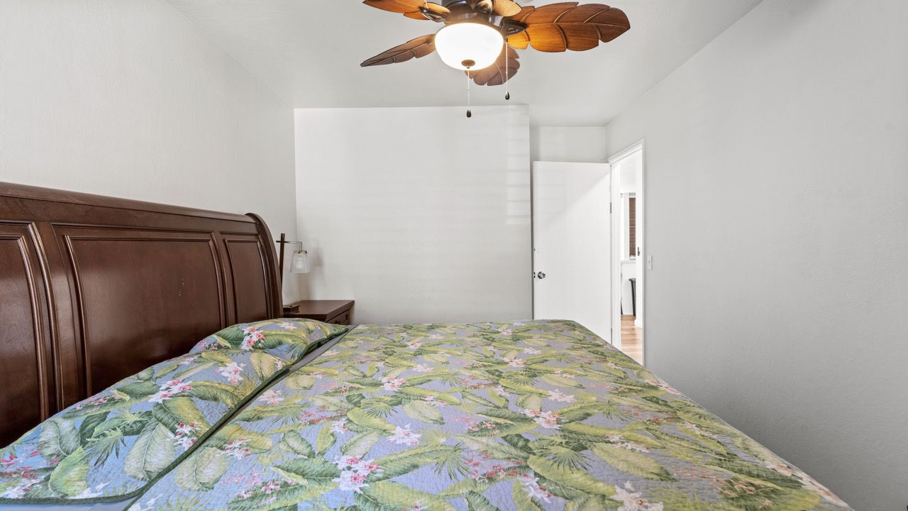 A bedroom with a bed and a ceiling fan.