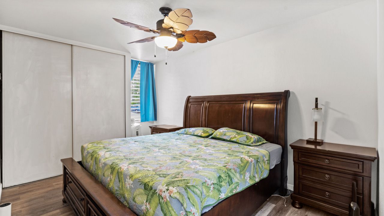 A bedroom with a bed , nightstand , and ceiling fan.