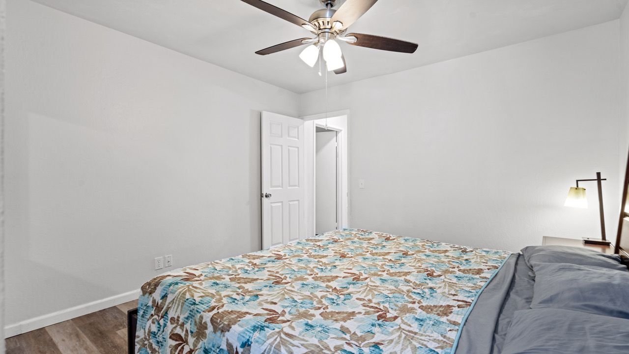 A bedroom with a bed and a ceiling fan.