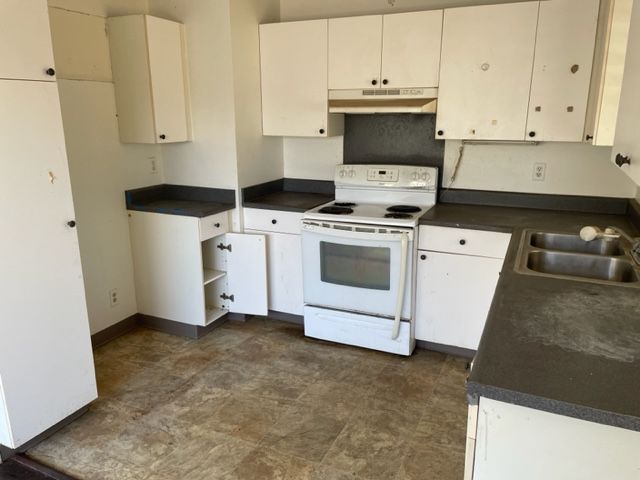 An empty kitchen with white cabinets and a white stove