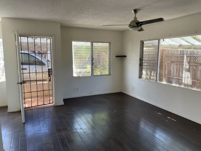 An empty living room with hardwood floors and a ceiling fan.